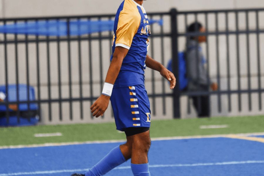 Soccer player smiling on blue field.