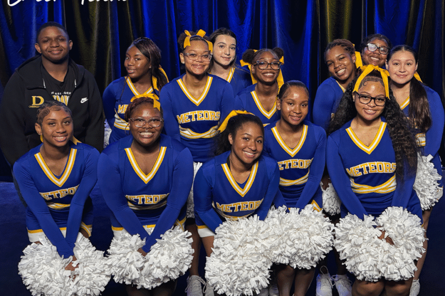Cheer team posing with pom-poms, smiling.